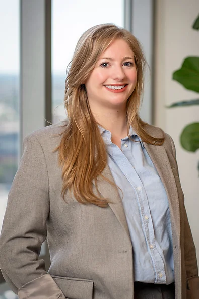 Attorney Paige Calabrese in a light brown blazer jacket with a light blue button down shirt smiling