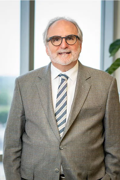 Attorney Lorin Subar smiling wearing a tan blazer, white jacket, and striped  tie